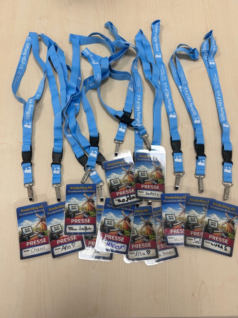 12 selbsterstellte Presseausweise der Grundschule Mühlenberg. Es handelt sich um laminierte Karten auf denen "Kinderblog AG. Grundschule Mühlenberg." und "Presse" sowie der Name des Kindes steht. Die Ausweise hängen an blauen Schlüsselbändern der Stiftung HELP e.V., die an der GS Mühlenberg Ganztags-Träger ist.